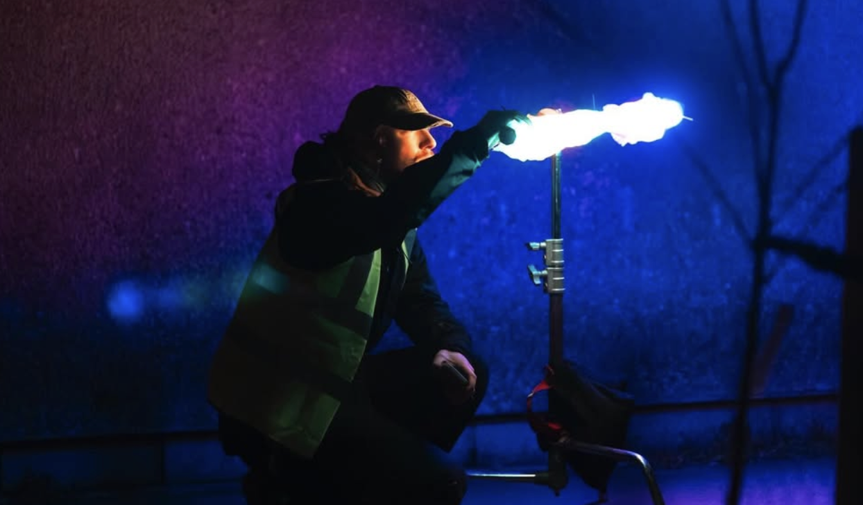 A filmmaker adjusts a light.